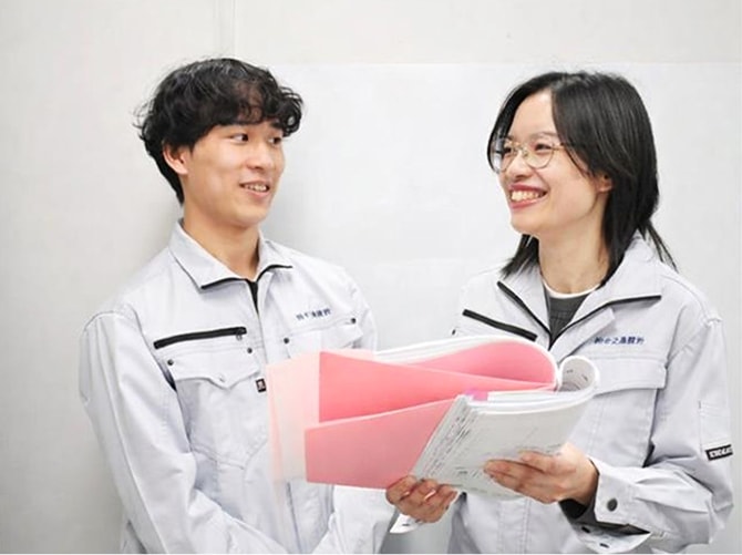 2人の社員が書類を手に笑顔で会話している様子