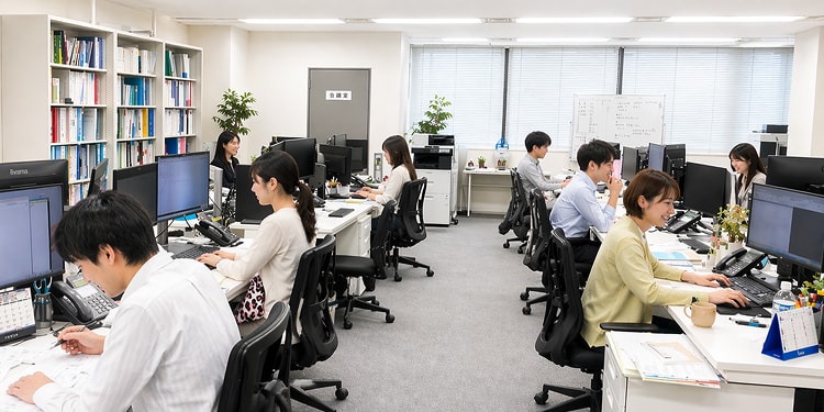 明るく清潔なオフィス環境で、デスクに向かい業務をおこなう社員たち